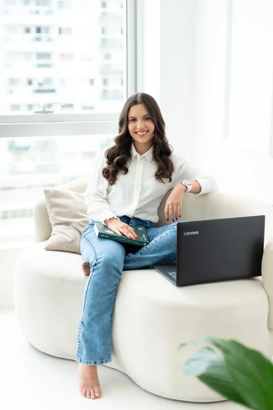 Rafaela Santos de Almeida, psicóloga, sentada no sofá com notebook